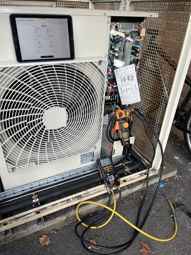 Air conditioning engineer using digital instruments to test refrigerant pressures, temperatures and electrical current
