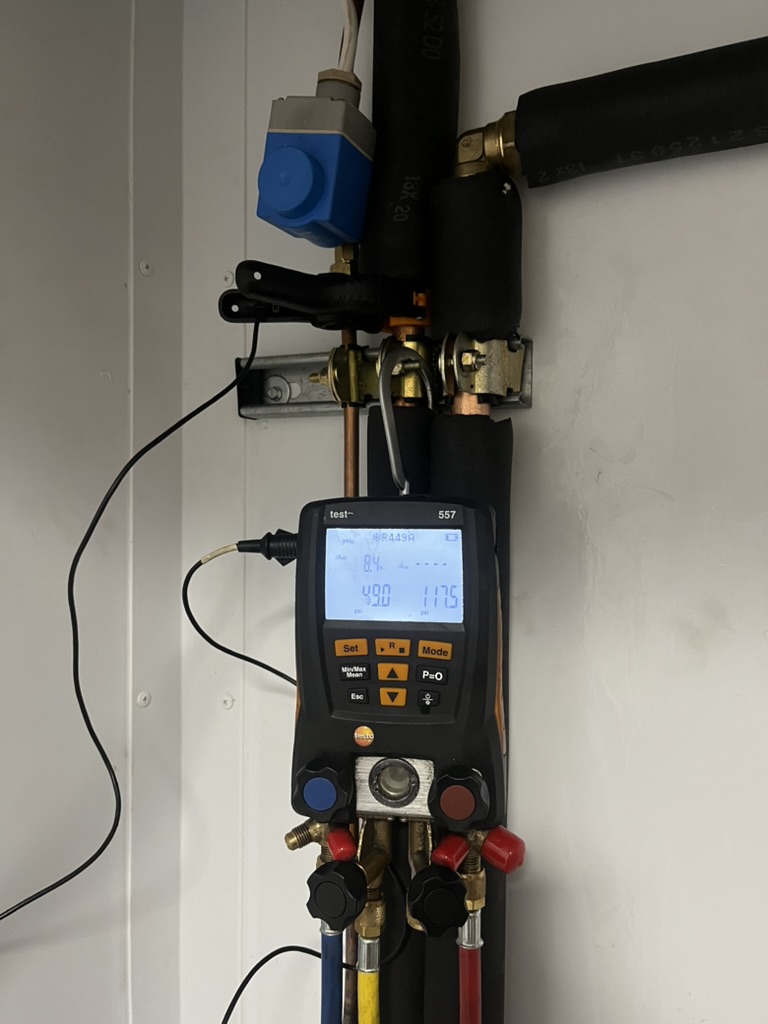 Digital refrigeration manifold and temperature probe being used to measure superheat