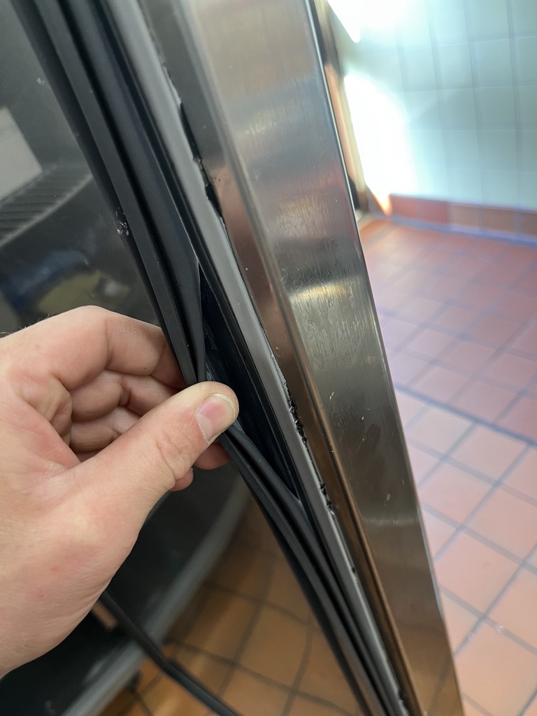 Torn door seal on a commercial refrigerated cabinet