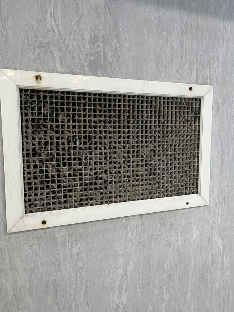 Ventilation grille heavily blocked with dust and debris