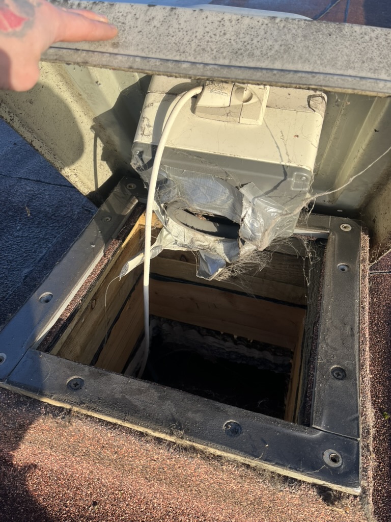 Damaged and poorly sealed flexible ventilation connection beneath a rooftop fan